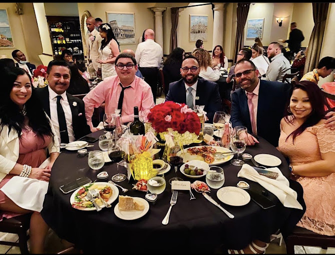 Guests celebrating a private buyout event at Ciao Italia Orlando — smiling group around a table with red floral centerpiece and Italian wine
